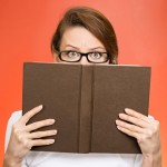 woman hiding behind book